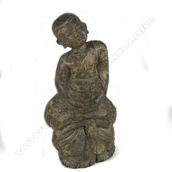 An Oriental carved wood figure of a child in lotus position