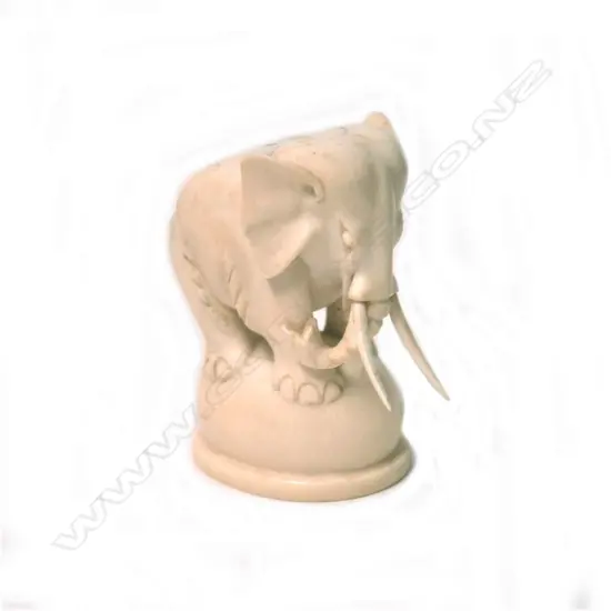 An early 20thC solid carved ivory elephant on ball stand