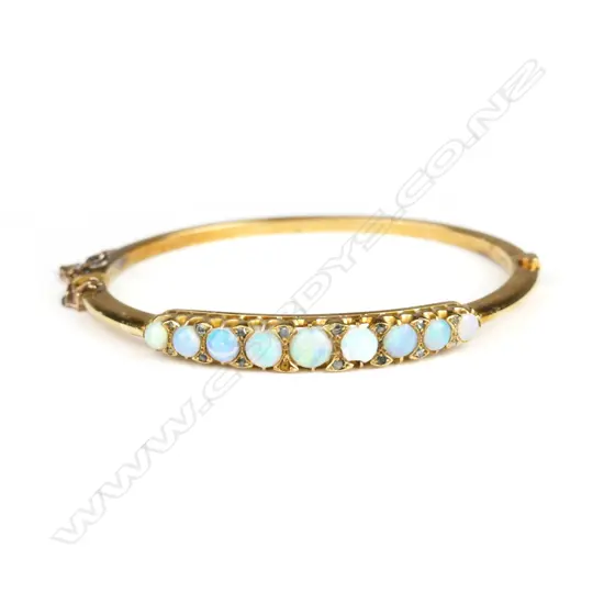 An early 20thC 15ct. yellow gold opal and diamond set hinged bangle