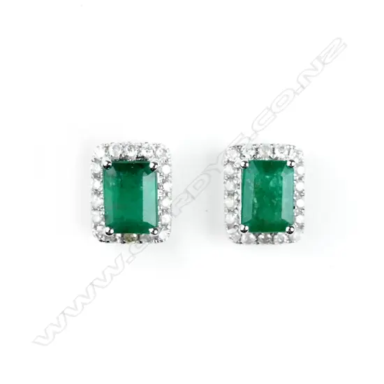 A pair of 14ct. white gold emerald and diamond stud earrings