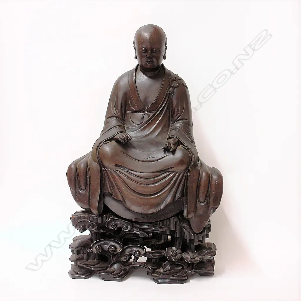An 19thC or earlier Chinese bronze seated monk on carved wooden stand Image 1++