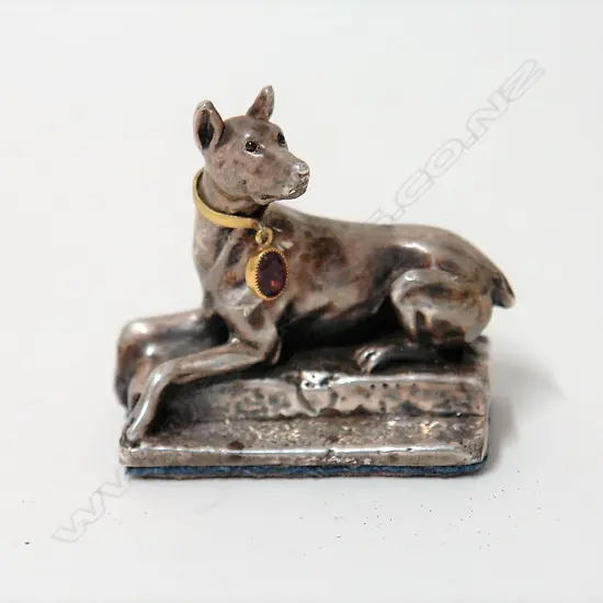 A modern silver recumbent dog paperweight
