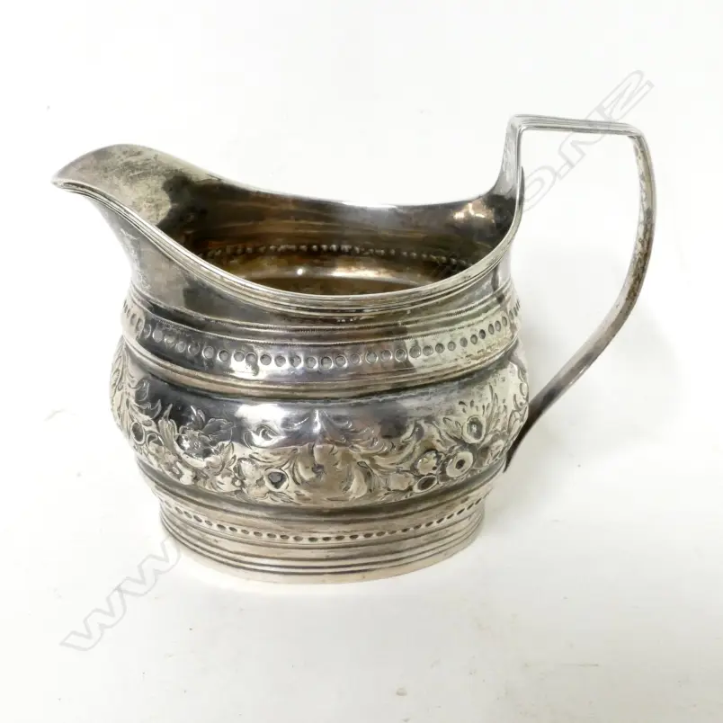 A Georgian flat-bottomed silver cream jug with embossed decoration Image 1++