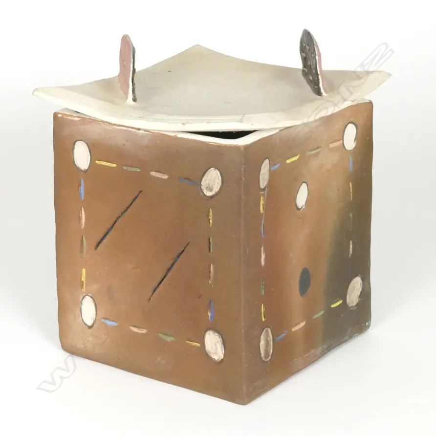 Denis O’Connor lidded cube with abstract patterns and a curved lid with 'dorsal fins'.  Brown stain and incised dashes and circles in bright colours.  The lid has an unglazed white body with two fins in brown and pink and pierced linear designs.  Stamped monogram.   The lid has a firing crack and one fin has been broken off professionally restored.  Ref:  Illustrated: 'Cone Ten Down' Image 1++