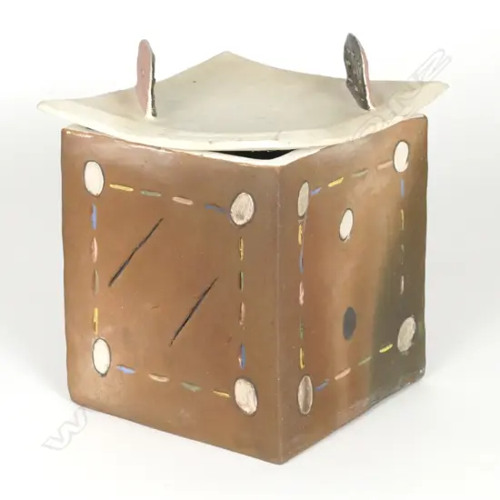 Denis O’Connor lidded cube with abstract patterns and a curved lid with 'dorsal fins'.  Brown stain and incised dashes and circles in bright colours.  The lid has an unglazed white body with two fins in brown and pink and pierced linear designs.  Stamped monogram.   The lid has a firing crack and one fin has been broken off professionally restored.  Ref:  Illustrated: 'Cone Ten Down'