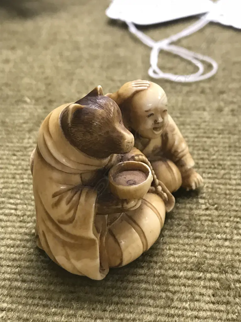 An early 20thC finely carved ivory netsuke of Tanuki seated with child Image 1++