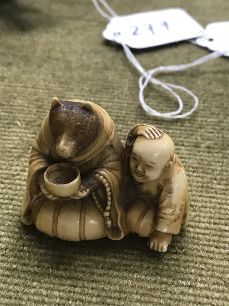An early 20thC finely carved ivory netsuke of Tanuki seated with child Image 1++
