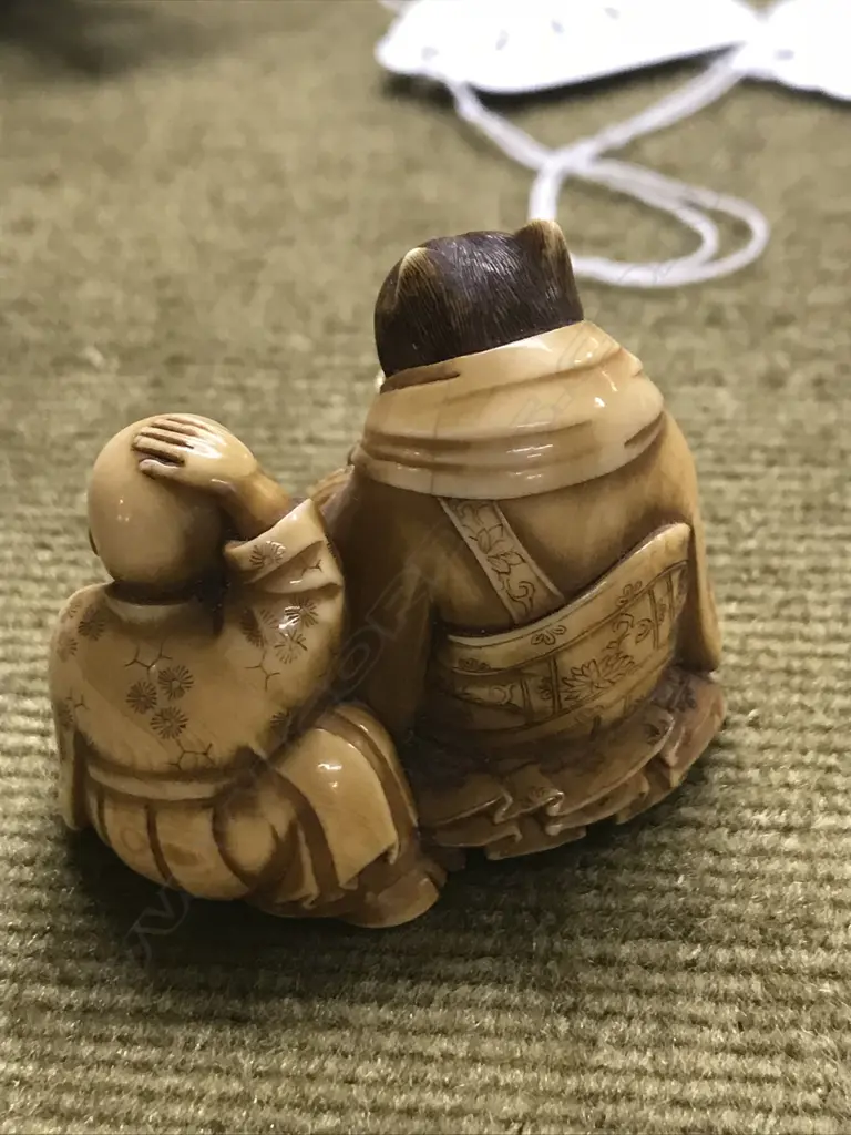 An early 20thC finely carved ivory netsuke of Tanuki seated with child Image 1++