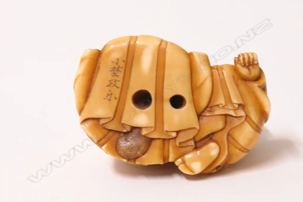 An early 20thC finely carved ivory netsuke of Tanuki seated with child Image 1++