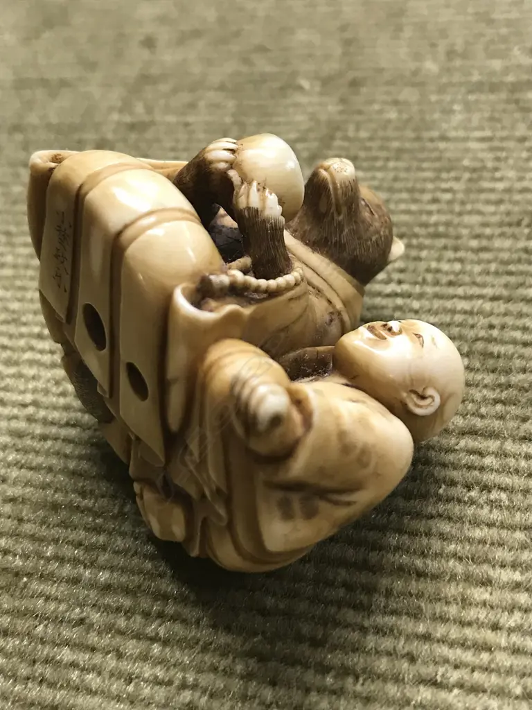 An early 20thC finely carved ivory netsuke of Tanuki seated with child Image 1++