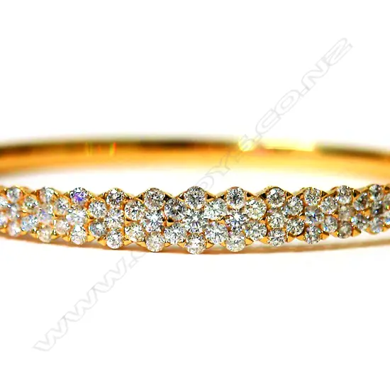 A lady's 18ct. yellow gold and diamond encrusted half-hinged bangle