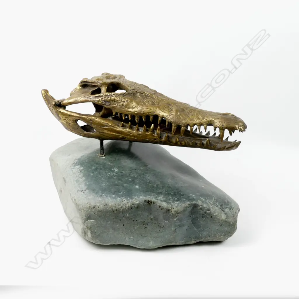 A brass sculpted crocodile skull on a serpentine boulder Image 1++