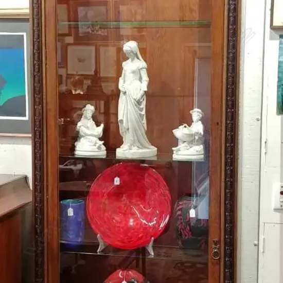 An early 20thC oak tall narrow glazed display cabinet