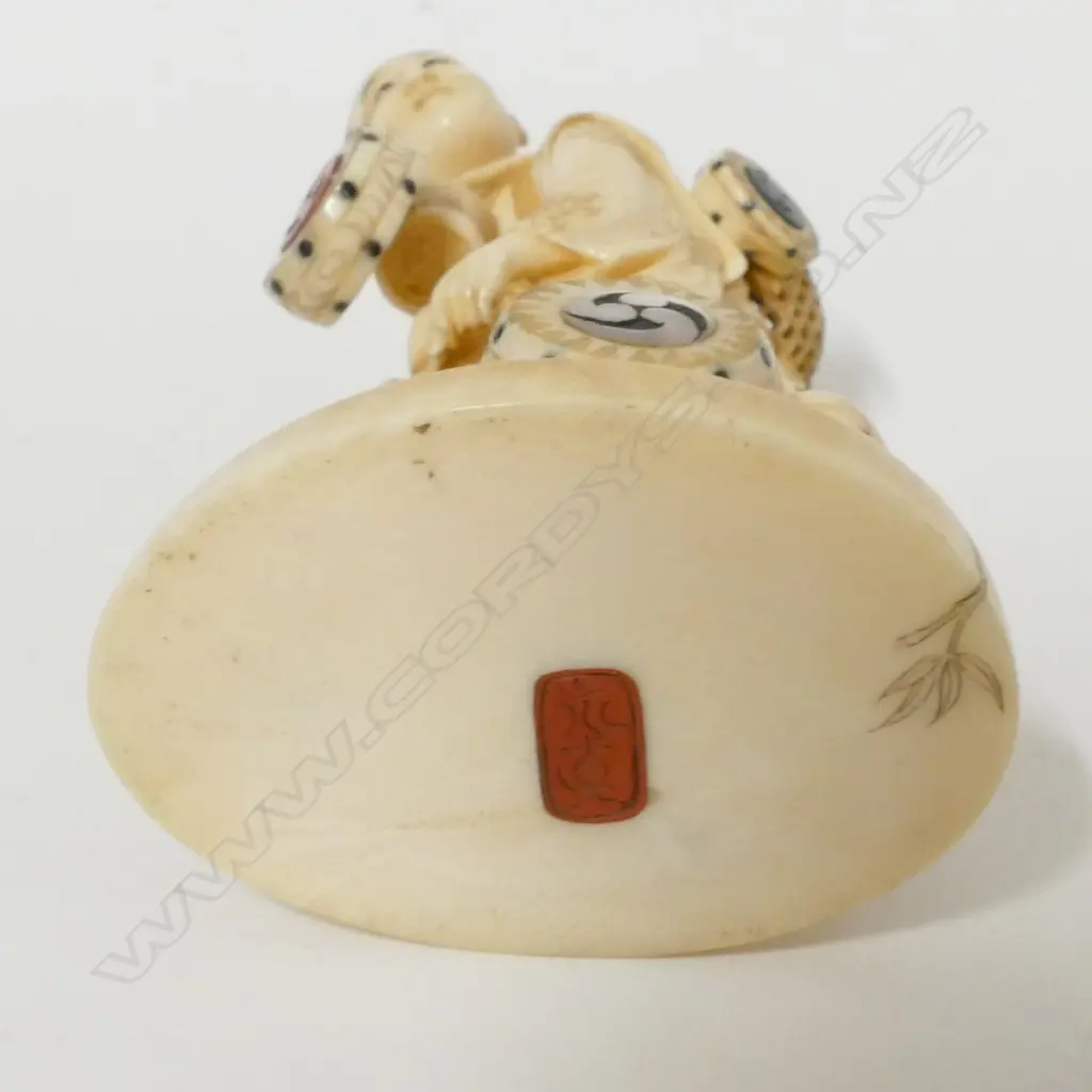 A Japanese Meiji period ivory okimono of a drum and basket seller Image 1++