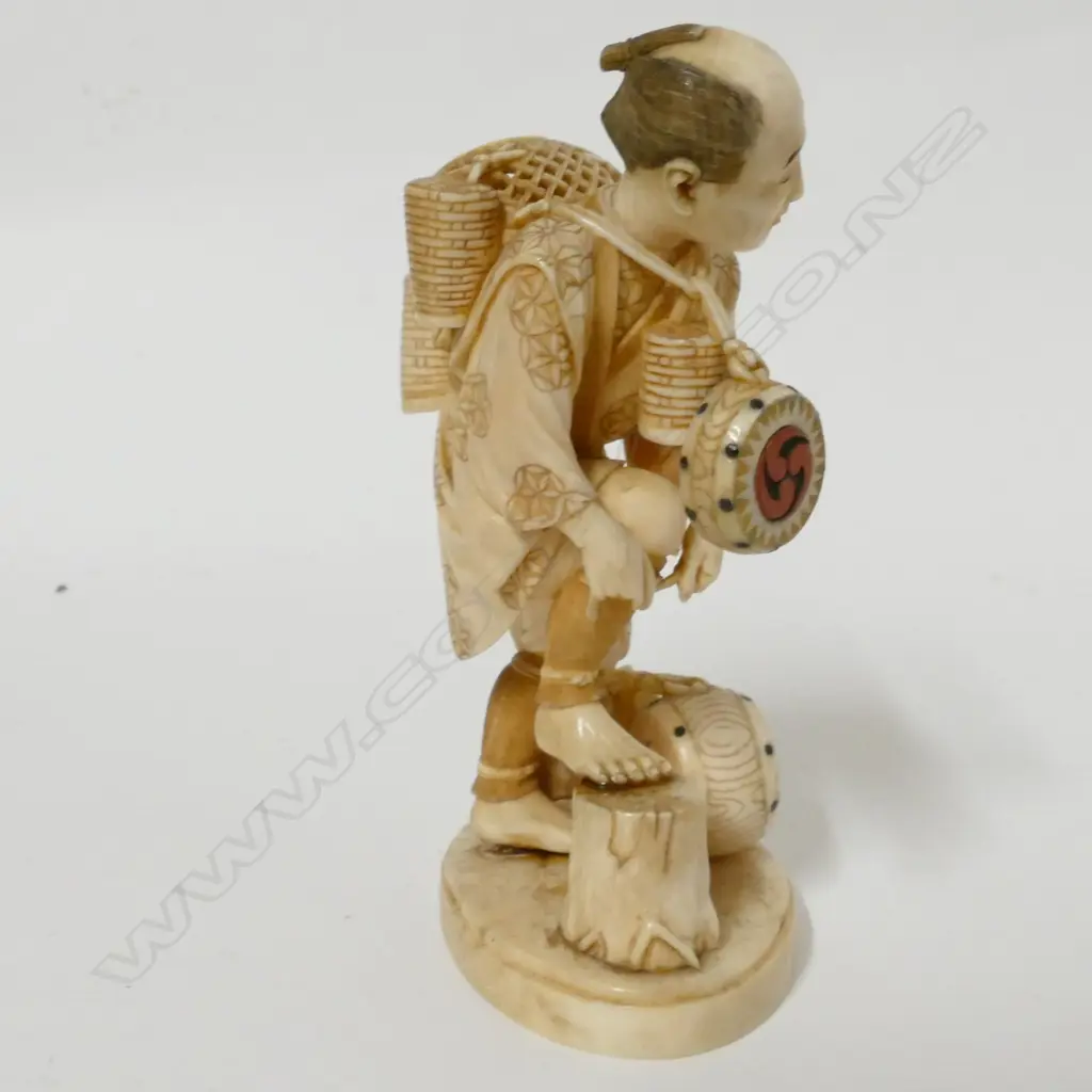 A Japanese Meiji period ivory okimono of a drum and basket seller Image 1++