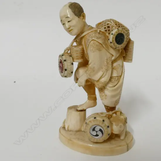 A Japanese Meiji period ivory okimono of a drum and basket seller