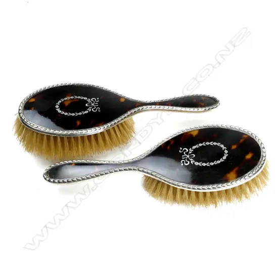 A pair of silver and tortoiseshell pique work hair brushes