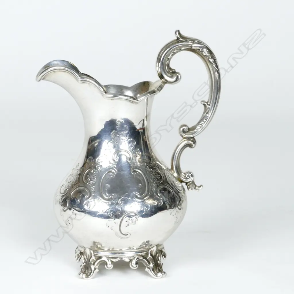 A Victorian silver baluster cream jug with embossed decoration and scroll handle Image 1++