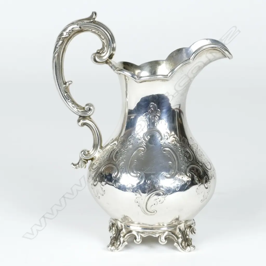 A Victorian silver baluster cream jug with embossed decoration and scroll handle Image 1++