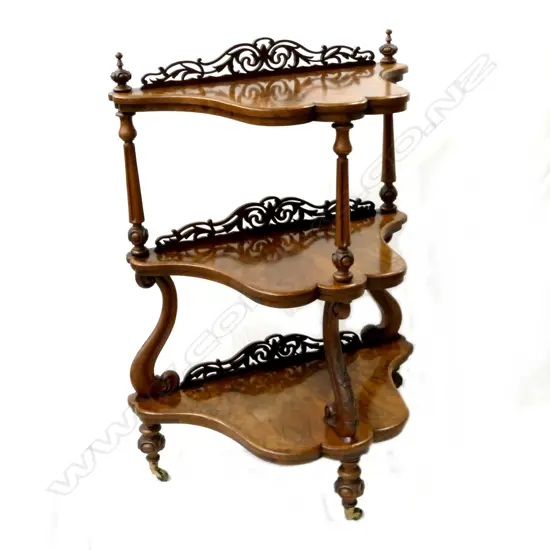 An unusual Victorian figured walnut serpentine three-stage whatnot