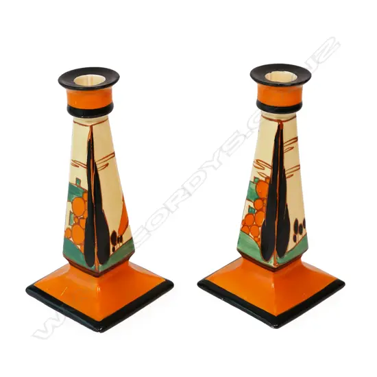 A pair of Clarice Cliff Bizarre orange 'Trees and House' candlesticks,