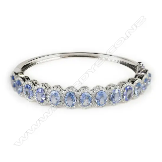 A 14ct white gold, sapphire and diamond halo bangle,