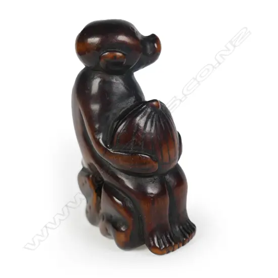 An early 19thC dark wood carved netsuke study of a monkey,