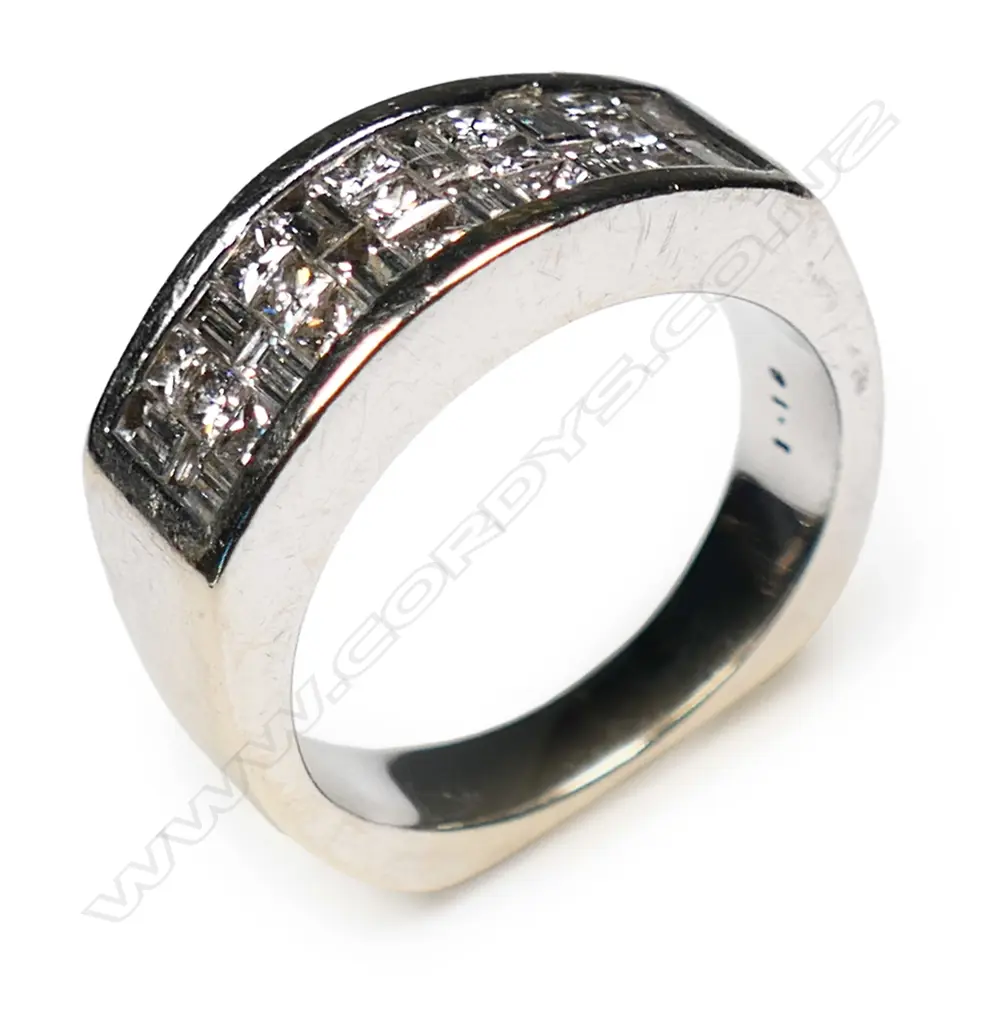 An 18ct white gold and diamond ring channel set with twelve baguette cut and fifteen round brilliant cut diamonds.  10.4gms, Image 1++