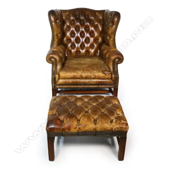 A leather button back wing back armchair and footstool,