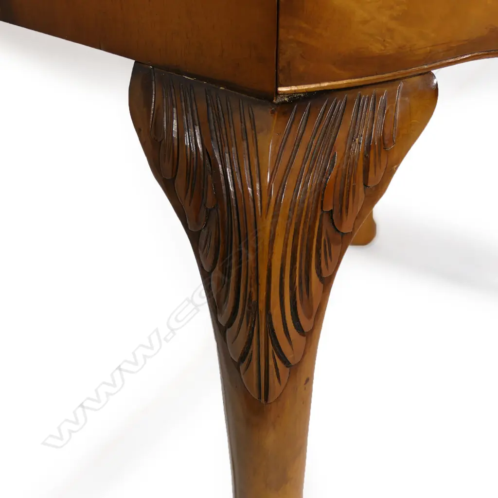 A c.1950 quality figured pale walnut drinks cabinet with the two bow front doors enclosing a mirrored back and base and with two glass shelves. Raised on cabriole legs with acanthus carved knees. 860 x 490 x 1480mm. Provenance: From the collection of Gerry and Valerie Bermel (of Travis Antiques, Wellington 1950's to 1986). Image 1++