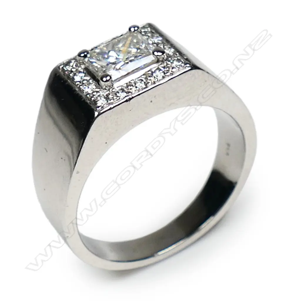 An 18ct white gold and diamond dress ring - a 0.72ct princess cut diamond (Colour F-G, Clarity VS-2), claw set and surrounded by fourteen round brilliant cut diamonds (Colour D-F, Clarity VS-S1), bead set in a flat panel mount, wide tapering shank. TDW. 0.92ct. Ring size K. Valuation available. Image 1++