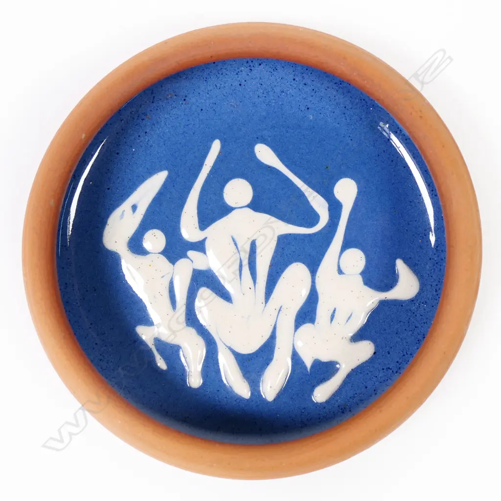 Len Castle ‘pin dish”  with a blue glaze inside with three stylised leaping human figures in white glaze. Red-brown coloured clay body. Stamped mark near the base. Dia.105mm. Image 1++