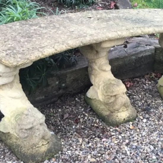 An old Haddonstone curved bench seat on triple dolphin fish base