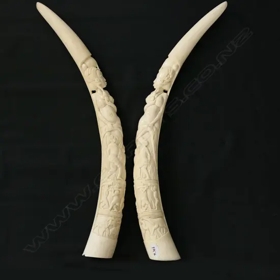 A pair of old African carved ivory tusks carved with a naked woman