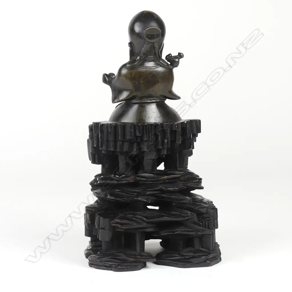An old Chinese cast bronze figure of a seated immortal on tall wood stand Image 1++