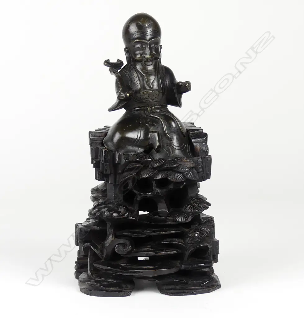An old Chinese cast bronze figure of a seated immortal on tall wood stand Image 1++