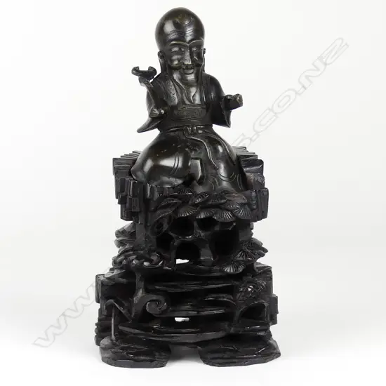 An old Chinese cast bronze figure of a seated immortal on tall wood stand