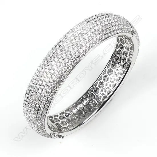 An impressive 18ct. white gold and entirely diamond set half hinged bangle