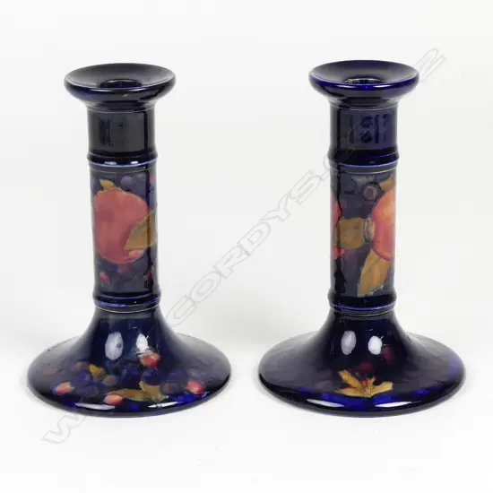 A pair of William Moorcroft pomegranate decorated candlesticks