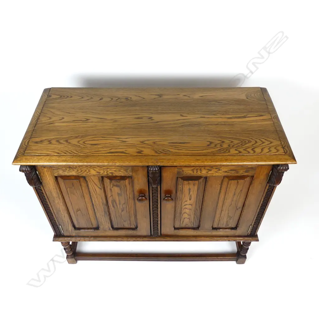 An early 20thC Jacobean style two-door panelled small oak cupboard Image 1++