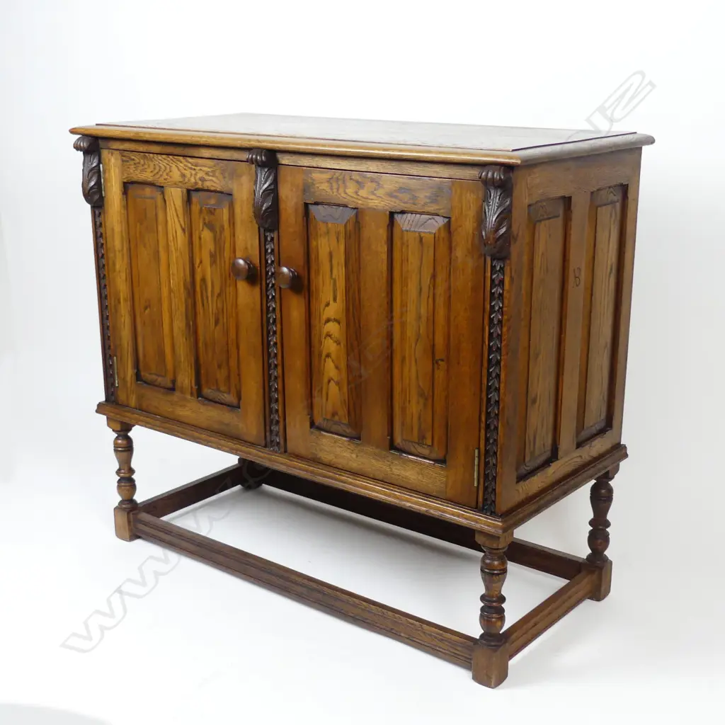 An early 20thC Jacobean style two-door panelled small oak cupboard Image 1++