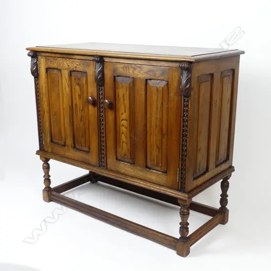 An early 20thC Jacobean style two-door panelled small oak cupboard