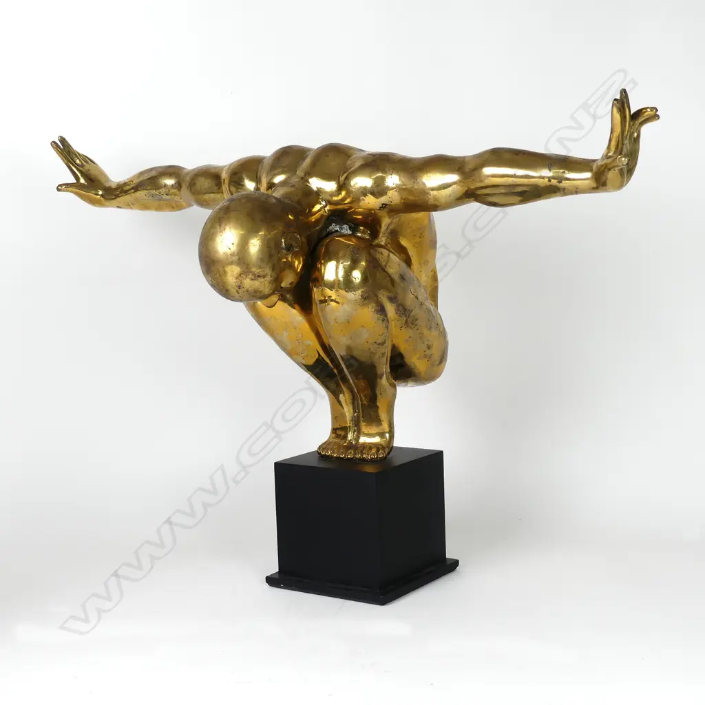 A polished bronze statue of a man in balanced toe stand pose Image 1++