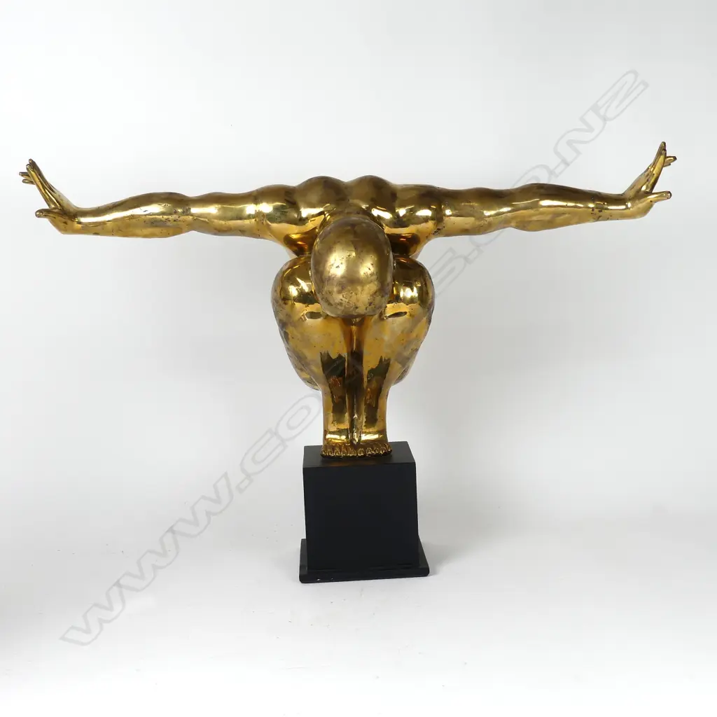 A polished bronze statue of a man in balanced toe stand pose Image 1++