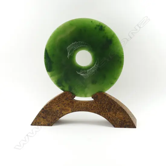 A pounamu bi disc on burr totara stand