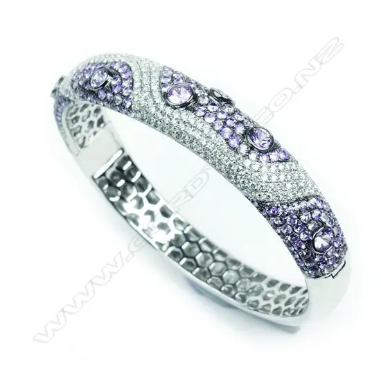 An encrusted 18ct white gold diamond and pink sapphire hinged bangle
