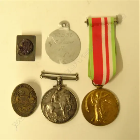 A pair of WWI war medals and associated badges