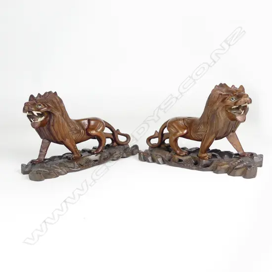 A pair of early 20thC Chinese hardwood carved prowling lions