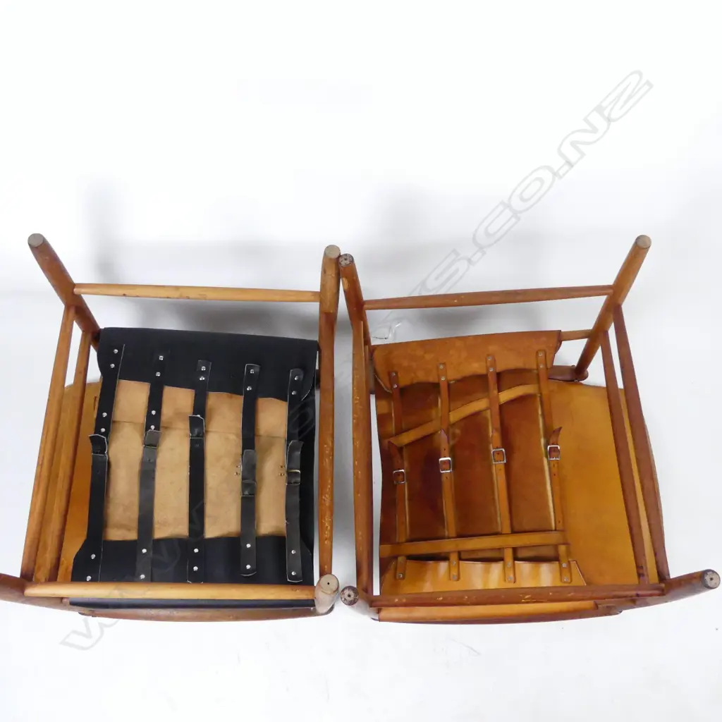 A pair of teak framed armchairs with aged leather seats and pivot mounted backs Image 1++