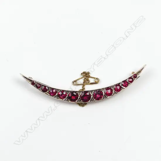 An early 20thC 9ct. rose gold faux ruby crescent brooch